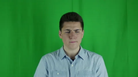 Young man sits thinking in front of greenscreen Stock Footage 59090589