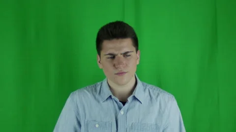 Young man sits thinking has an a-hah moment in front of greenscreen Vidéo 59090981