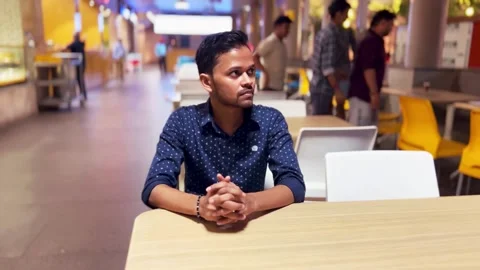 A young man sits thoughtfully at a modern Varanasi restaurant Stock Footage 285025973