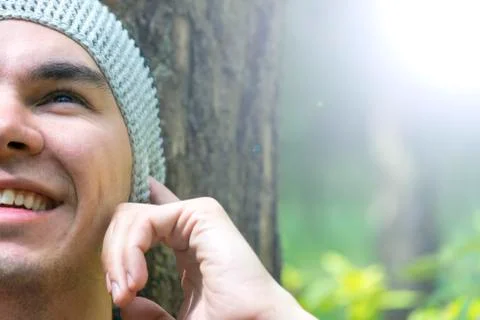 A young man sits under a tree and listens to music Foto stock
