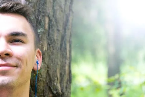 A young man sits under a tree and listens to music Stock-Fotos