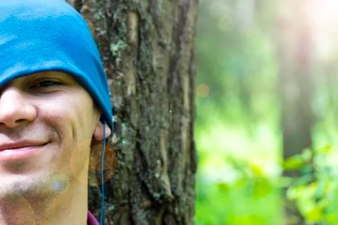 A young man sits under a tree and listens to music Stock Photos