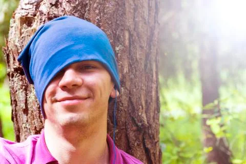 A young man sits under a tree and listens to music Stock Photos