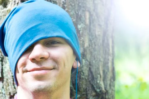 A young man sits under a tree and listens to music Stock Photos