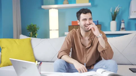 Young man sitting alone at home thinking about happy moments and smiling. Stock Footage 236294699