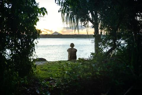 Young Man Sitting Alone on Meadow in a Seashore Looking the Sunset in Noosa,Q Stock Photos