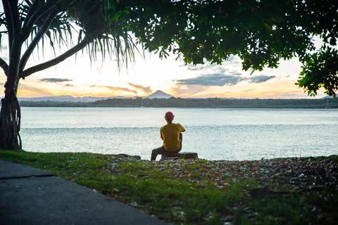 Young Man Sitting Alone on Meadow in a Seashore Looking the Sunset in Noosa,Q Stock Photos