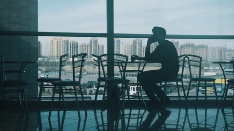 Young man sitting alone at table in shopping mall's cafe using a smartphone Stock Footage 76045717
