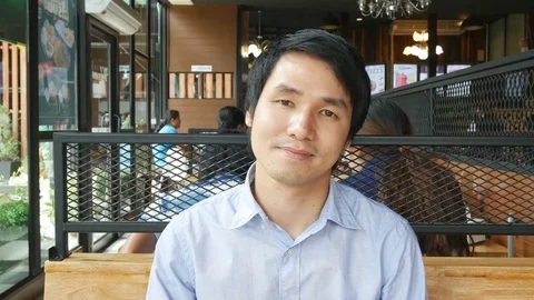 Young man sitting and smiling in a restaurant Stock-Footage 77269253