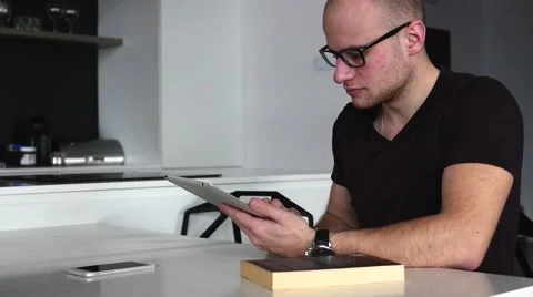 Young man sitting and using mobile and tablet pc. Book is on the table. 스톡 동영상 62021024