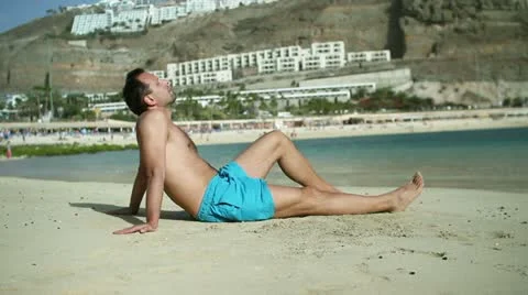 Young man sitting on the beach HD Stock Footage