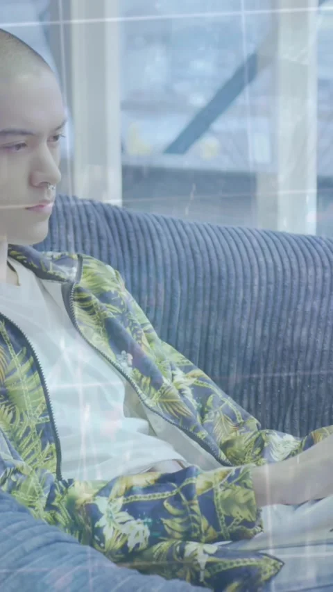 A young man is sitting in a beanbag and using a laptop computer in a modern open Stock Footage 343682515