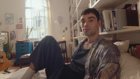 Young Man Sitting on Bed and Posing for Camera in Sunlit Room Stock Footage 243237198