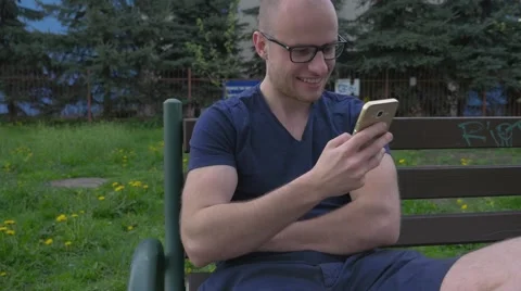 Young man sitting on the bench and using mobile phone. Stock Footage 62520576