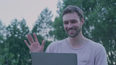 A young man is sitting on a bench and communicating on a laptop.Red Helium 8K Stock Footage 156204675