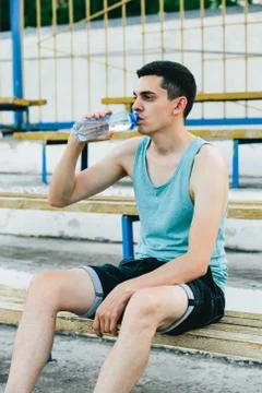 A young man sitting on a bench and tying his shoelaces in the fresh air Stock Photos