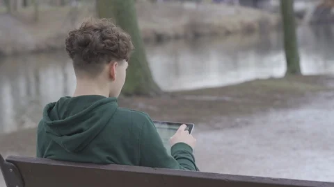 Young man sitting on the bench in the park and using his surface labtop 스톡 동영상 111617169