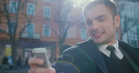 A young man sitting on a bench uses a smartphone Stock Footage 73227934