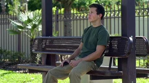 Young man sitting on bench watching traffic, 4K Stock Footage 48703108