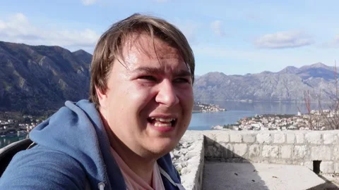 Young man is sitting on brick parapet and talking enthusiastically, gesturing Stock Footage 170733886