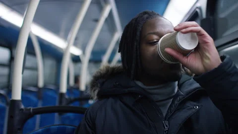 Young man sitting on a bus looking around and sipping from a coffee cup 스톡 동영상 225489955