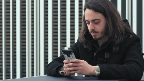 Young man sitting at the cafe quickly scrolls the phone keypad Stock Footage 240339088