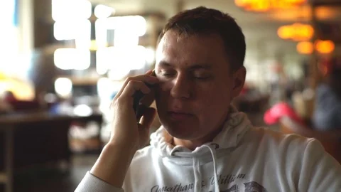 Young man sitting in cafe using phone Stock Footage 76299398