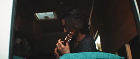 Young man sitting in camper van playing the guitar Stock Footage 203584217