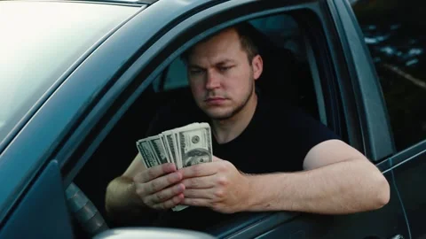A young man sitting in a car counts money. Stock Footage 131342300