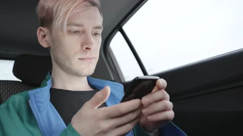 Young man sitting in a car typing text message 動画素材 194141853