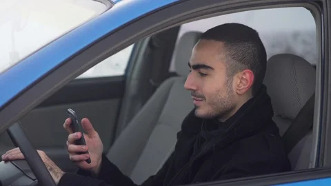 Young man sitting in car, using his smartphone  库存影片 103942348