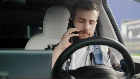 Young man sitting in the car while talking on the mobile phone. Stock Photos