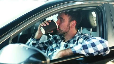 Young man sitting in the car while drinking coffee. Transport, lifestyle, people Stock Photos
