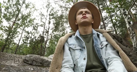 Young man sitting on cliff in forest Stock Footage 95420840