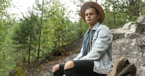 Young man sitting on cliff in forest Stock Footage 95420908