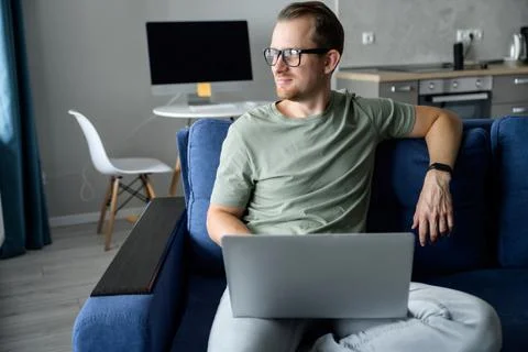 Young man sitting on the comfortable couch and using a laptop Stock Photos