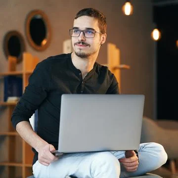 Young man sitting with computer. Freelancer in glasses working with laptop Foto stock