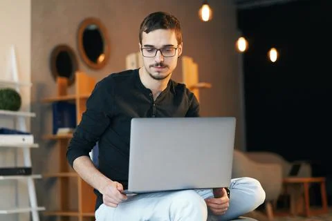 Young man sitting with computer. Freelancer in glasses working with laptop Stock Photos