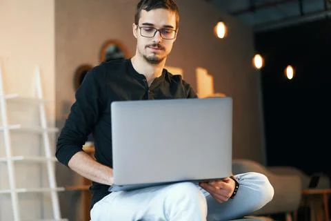 Young man sitting with computer. Freelancer in glasses working with laptop Stock Photos