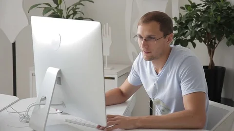Young man is sitting at computer at table and chatting indoors. Video stock 81652017
