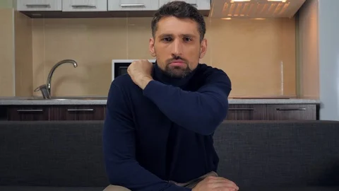 A young man is sitting on the couch and is gets angry and swears on a TV show Stock Footage 121839408