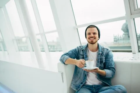 Young man sitting on the couch drinking a cup of coofee Stock Photos