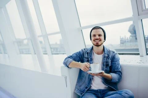Young man sitting on the couch drinking a cup of coofee Stock Photos