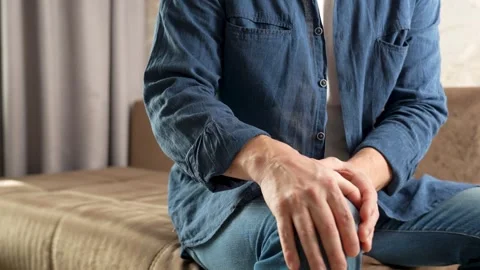 Young man sitting on couch, having knee pain and feel painful of joint Stock Footage 270730225