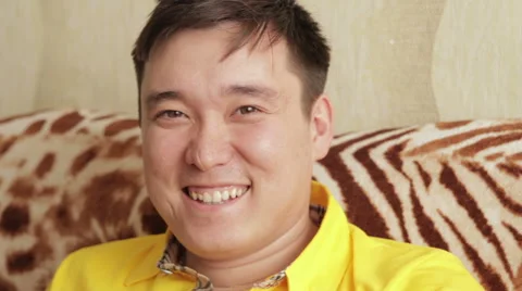 Young Man Sitting on the Couch, Looking at Camera with a Smile Stock Footage 61413932