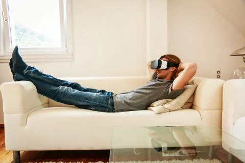 Young Man Sitting On Couch, Using Vr Glasses 写真素材