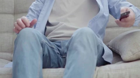 A young man is sitting on the couch watching TV Stock Footage 179960402