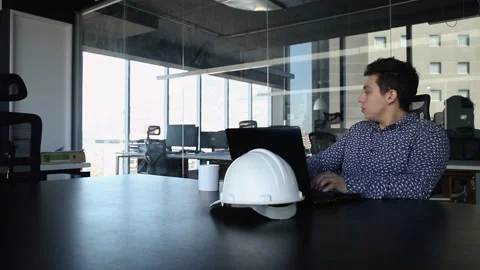 Young man sitting at desk at work next to his laptop. typing and drinking cof Stock Footage 147361293