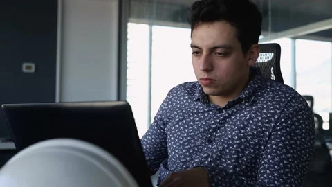 Young man sitting at desk at work next to his laptop. typing and drinking cof Stock Footage 147362630
