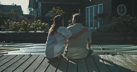 Young man sitting on the dock when girl kissing him on the cheek Stock Footage 221317842